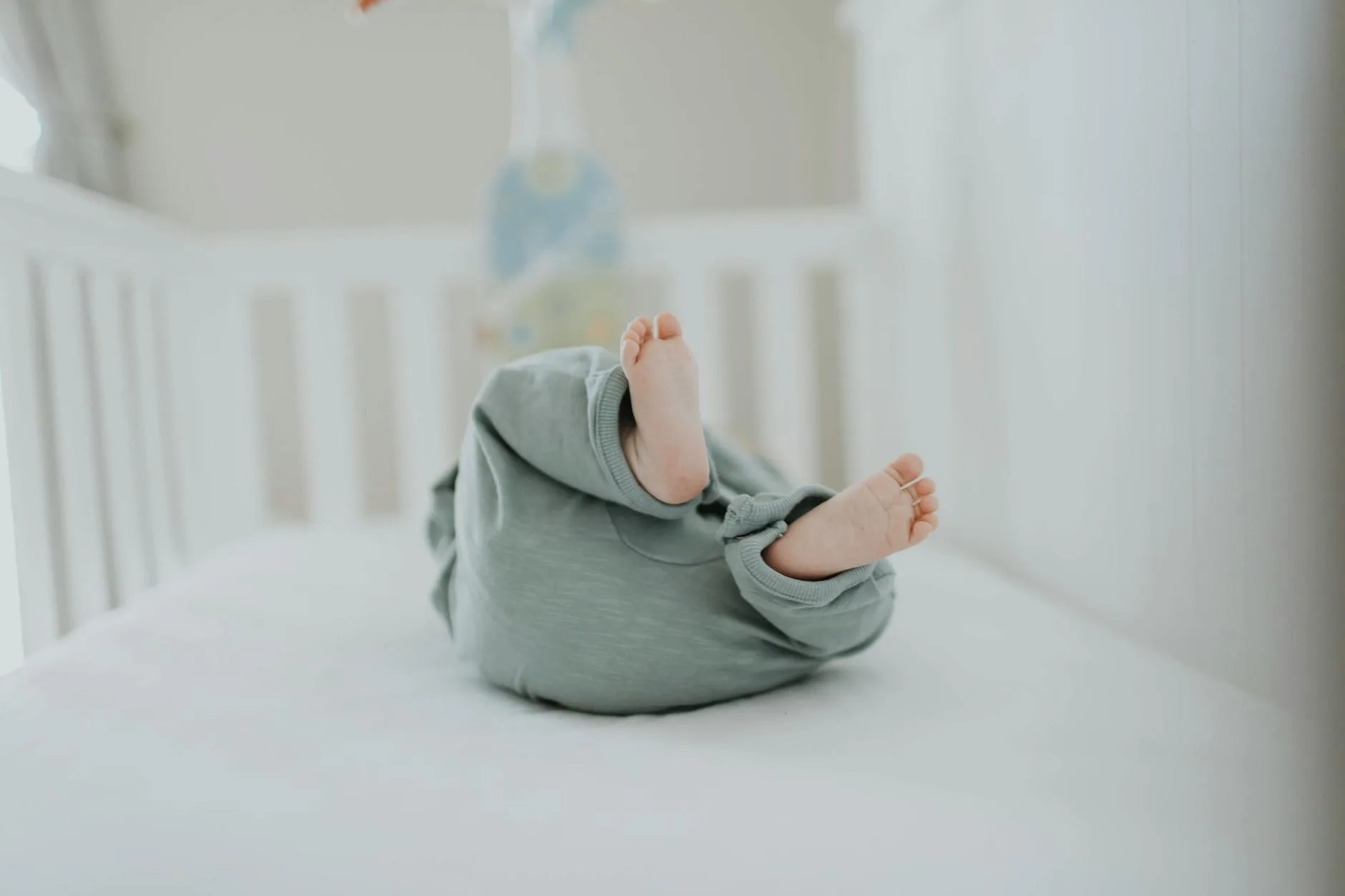 Baby crib with fitted sheet and firm mattress in nursery