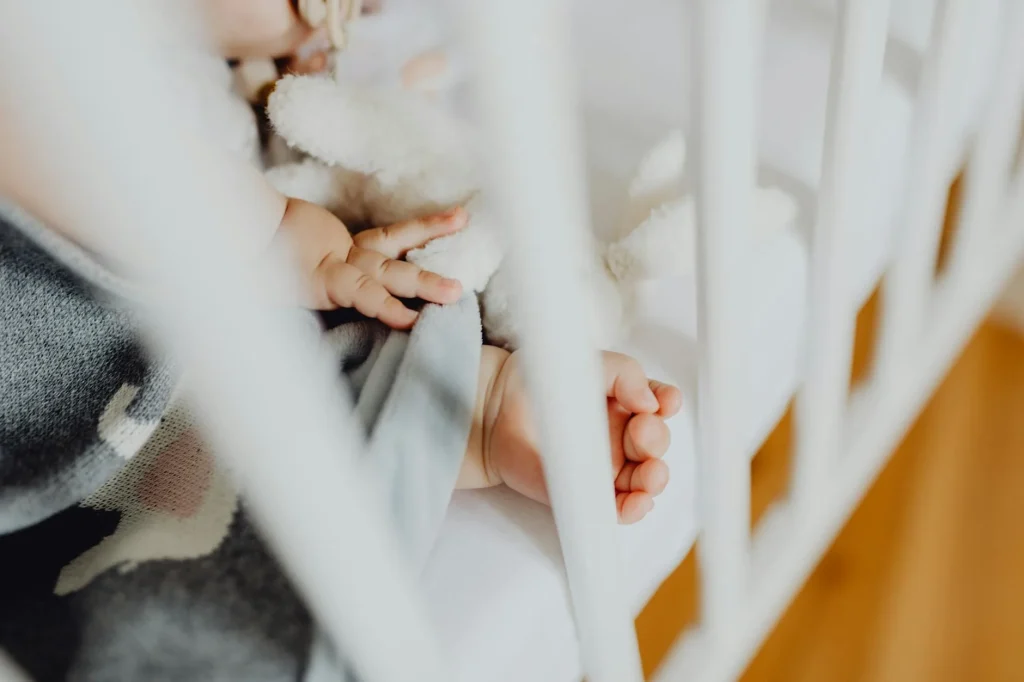 Baby sleeping peacefully in a dimly lit nursery with a baby monitor nearby