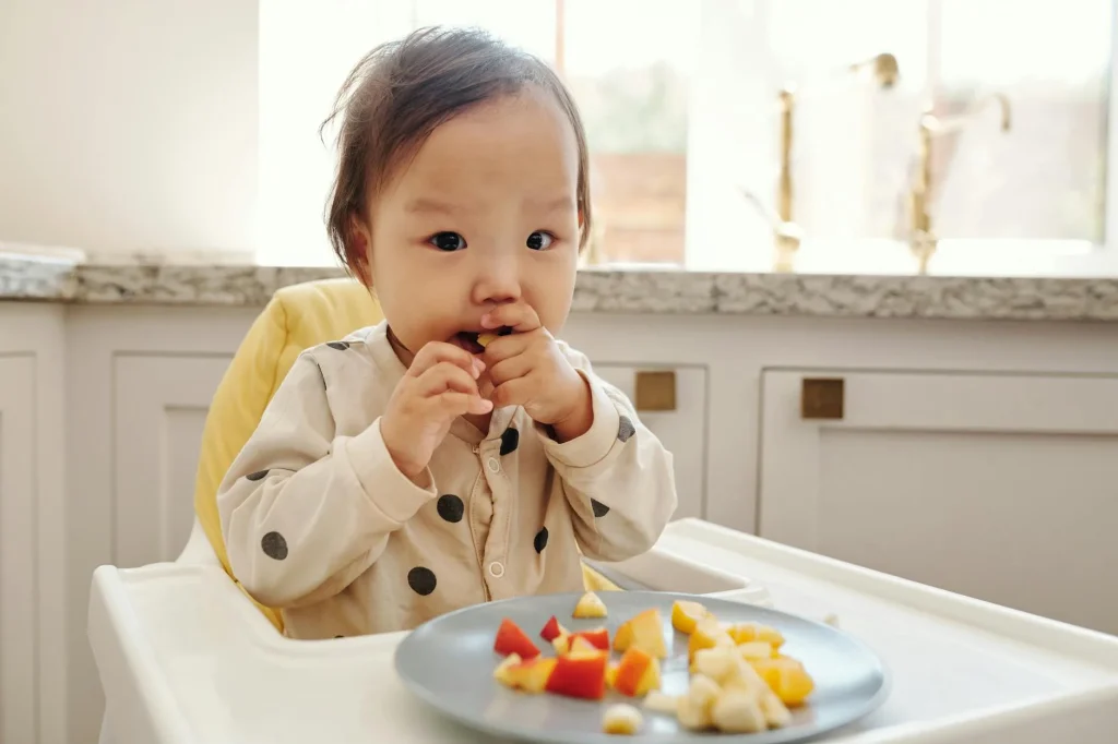 Baby in a highchair trying solid foods for the first time