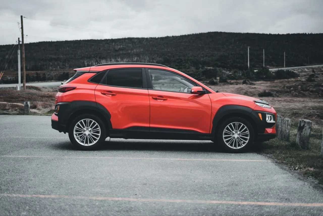 Red SUV parked on a rural road with hills in the background