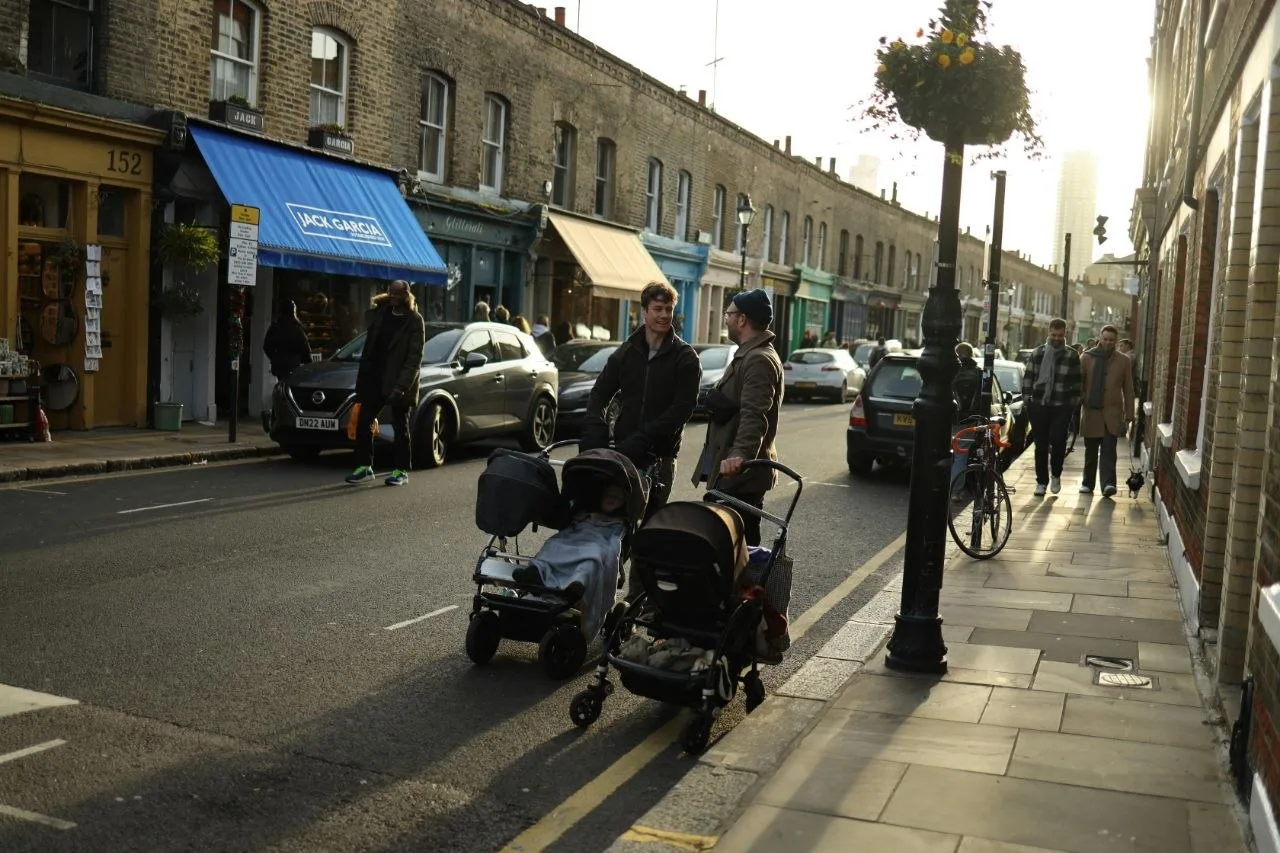 Two dads with pushchairs chatting on a London shopping street