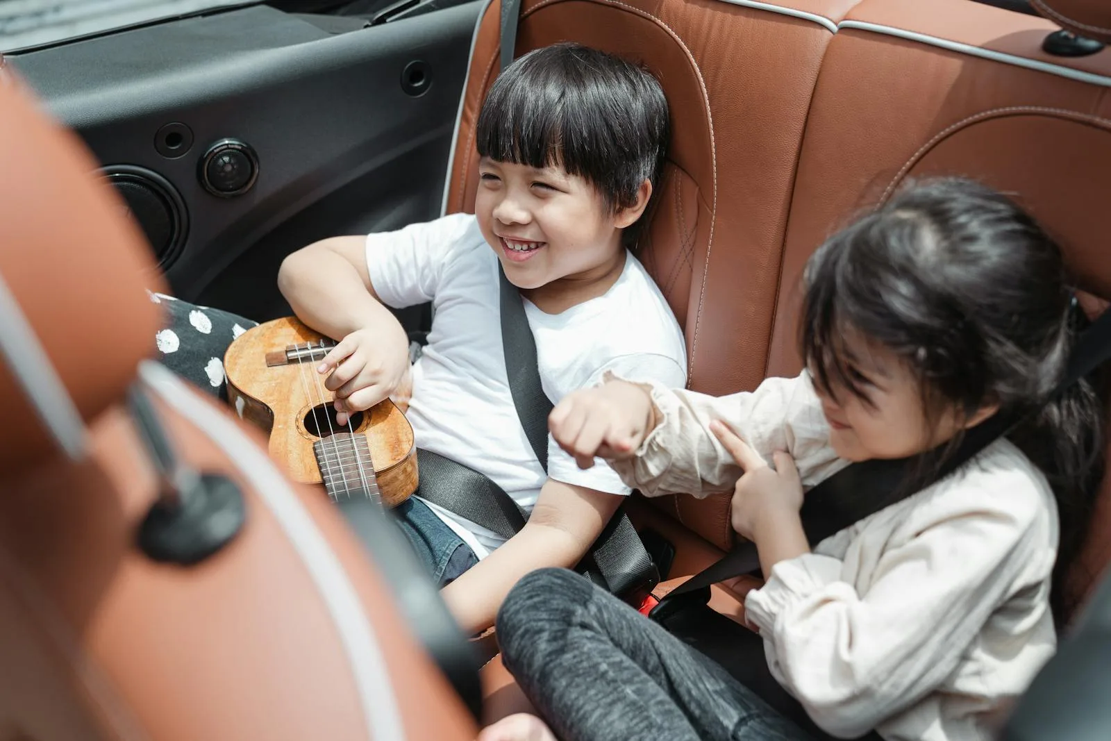 Two happy children buckled into the back seat of a car ready for a family journey
