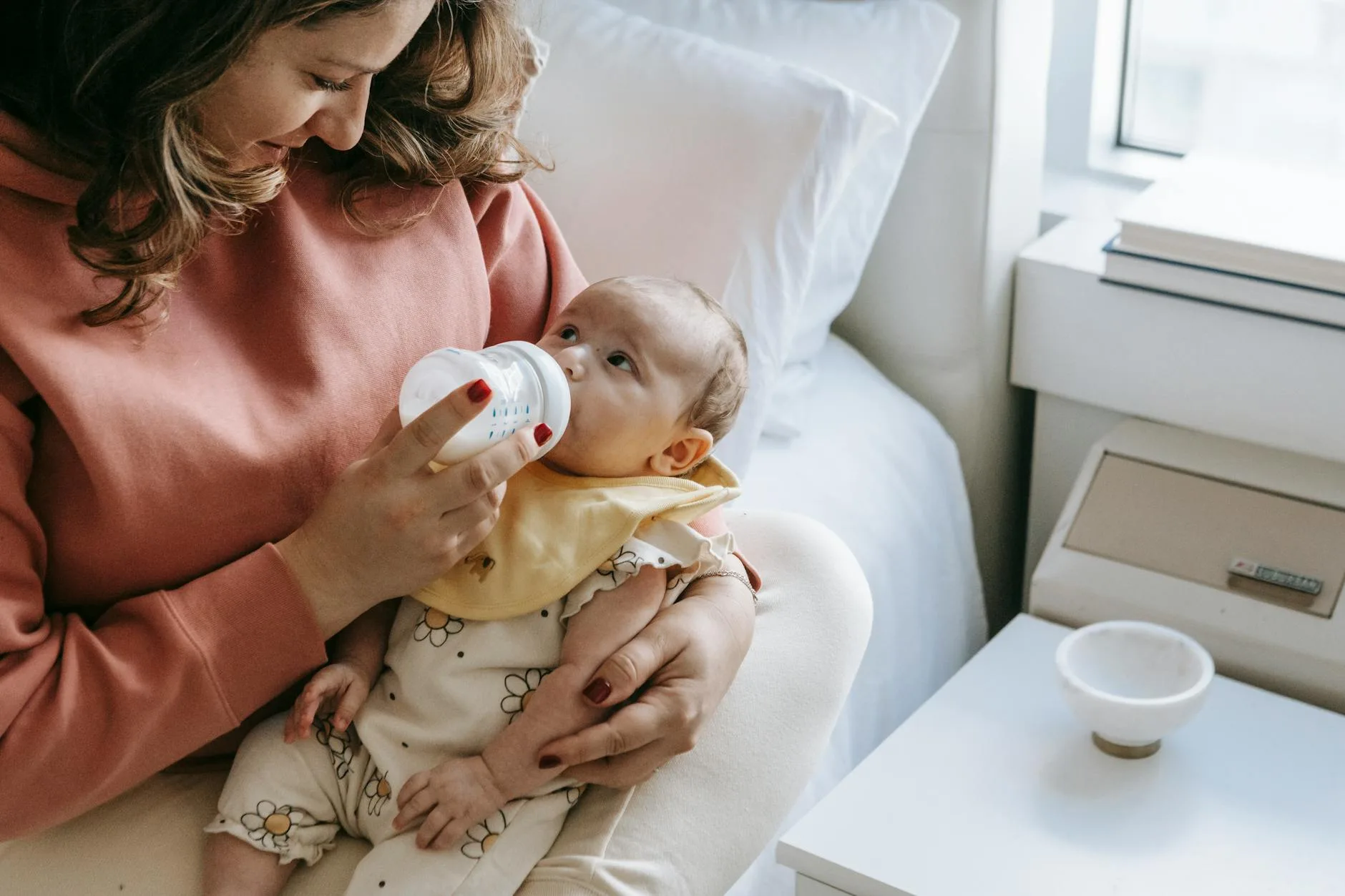 Mother bottle feeding baby in dim light during a night feed