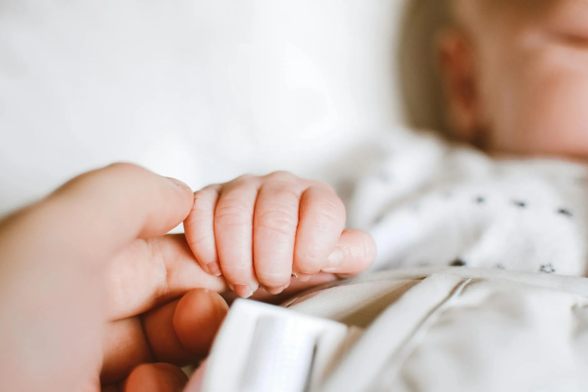 Parent gently comforting a baby in their cot at bedtime