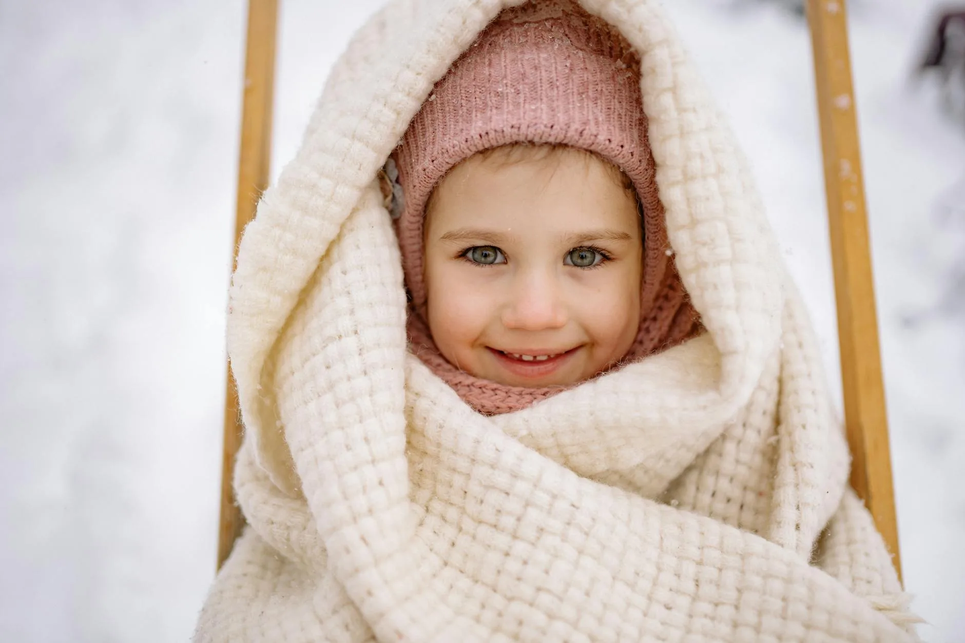 Toddler bundled up in a warm hat and blanket during winter