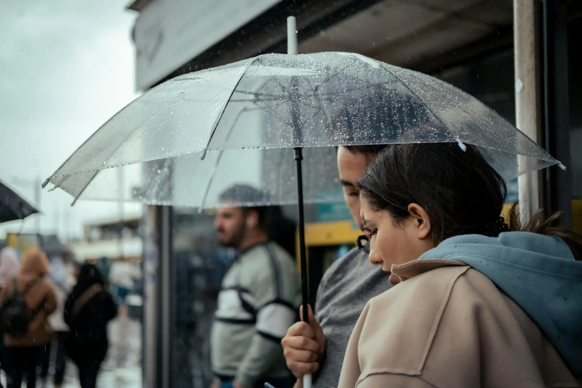 Couple walking through rain with an umbrella on a city street