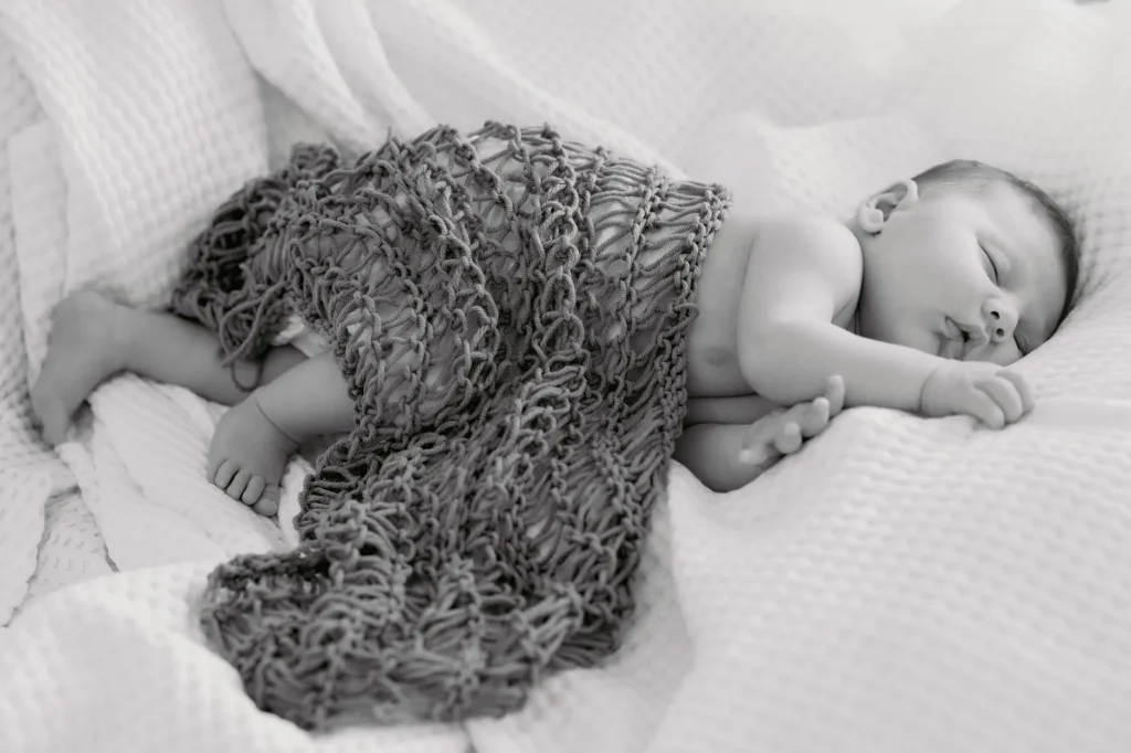 Baby sleeping peacefully in a cot without swaddle
