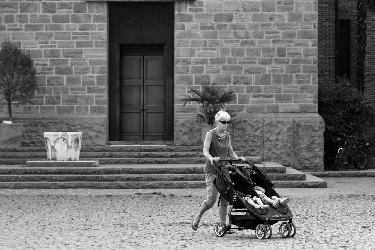 Woman pushing a double pushchair along an urban street
