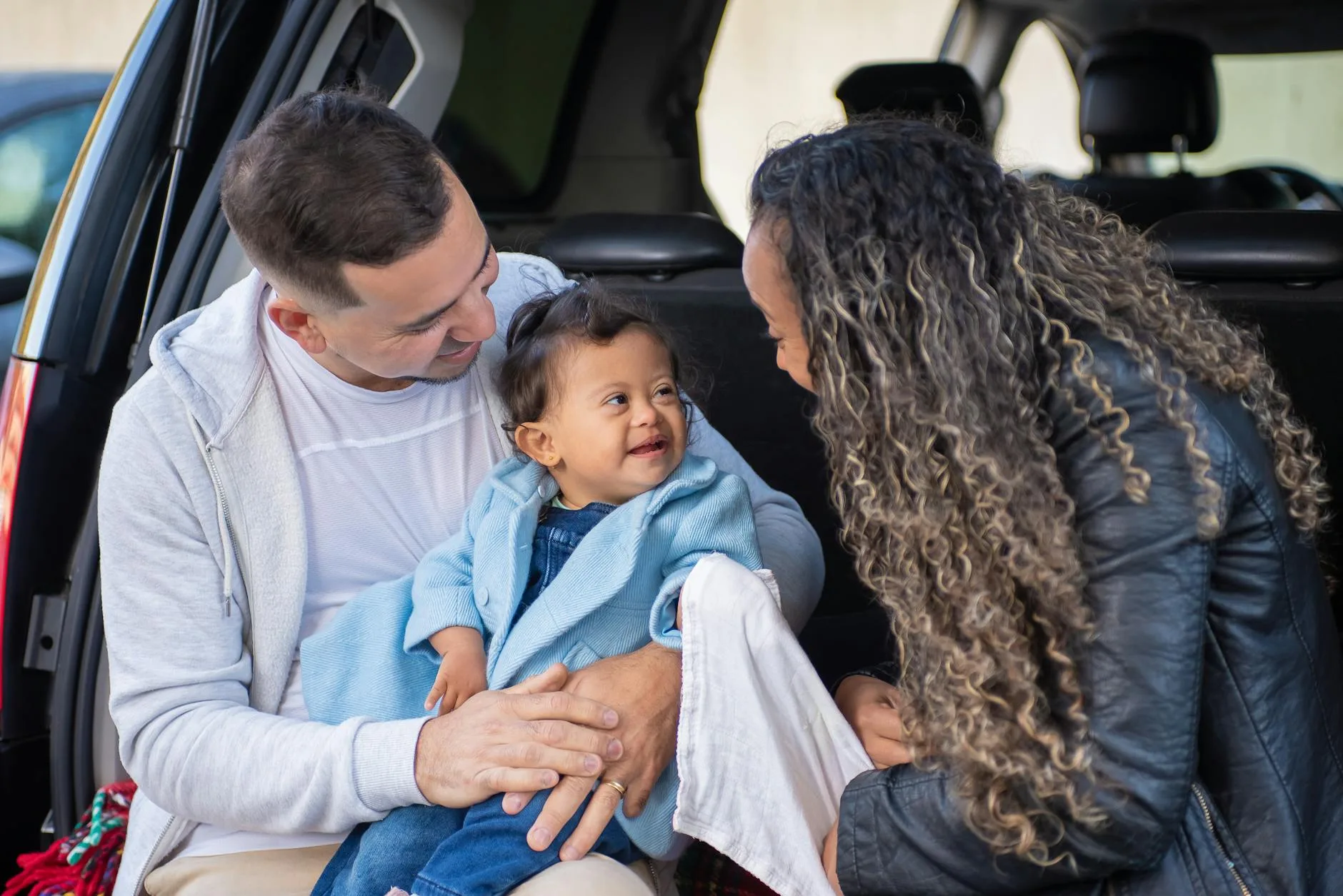 Parent placing a child into a car for a journey
