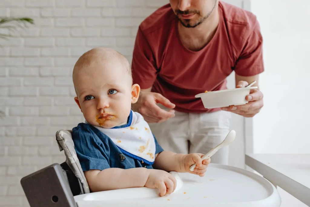 Baby eating weaning food in a highchair