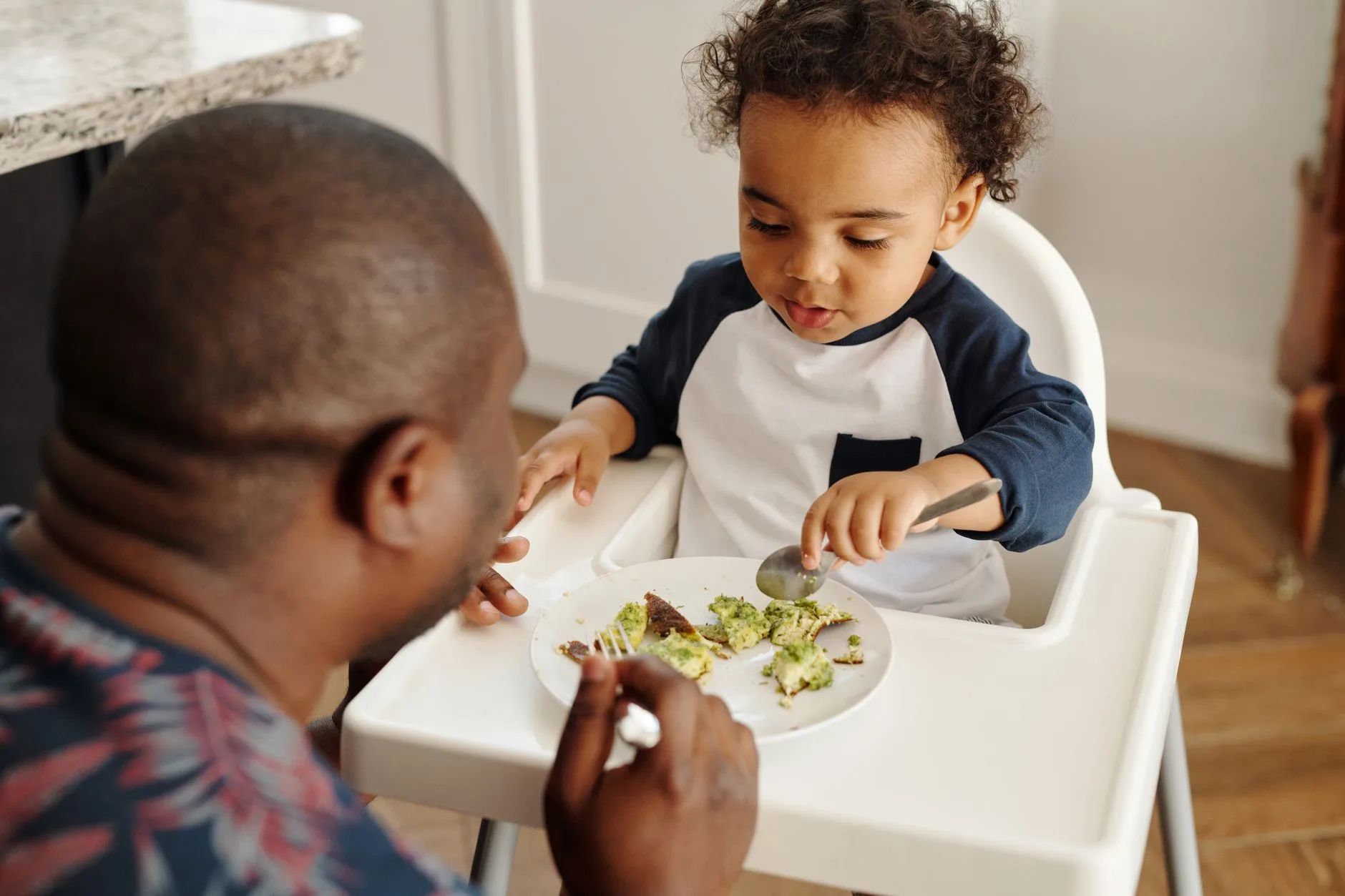 Baby self-feeding soft food in a highchair during weaning
