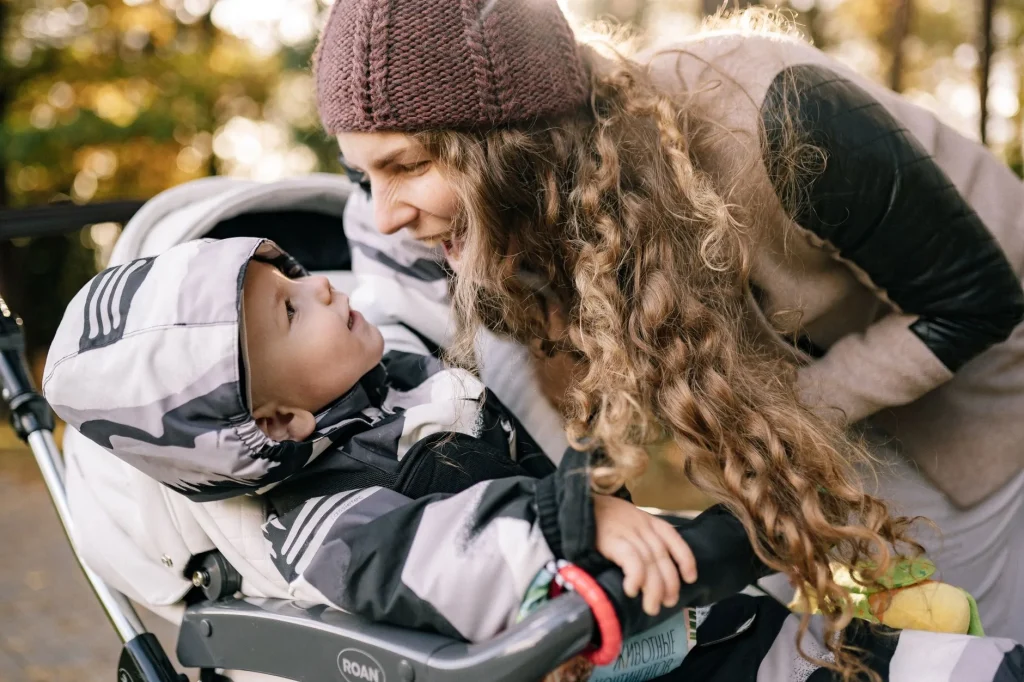 Parent pushing a baby pushchair through a park